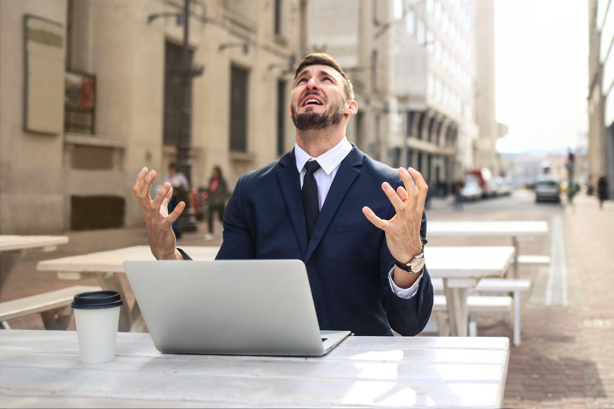 A man in a business suit looks up at the sky asking 